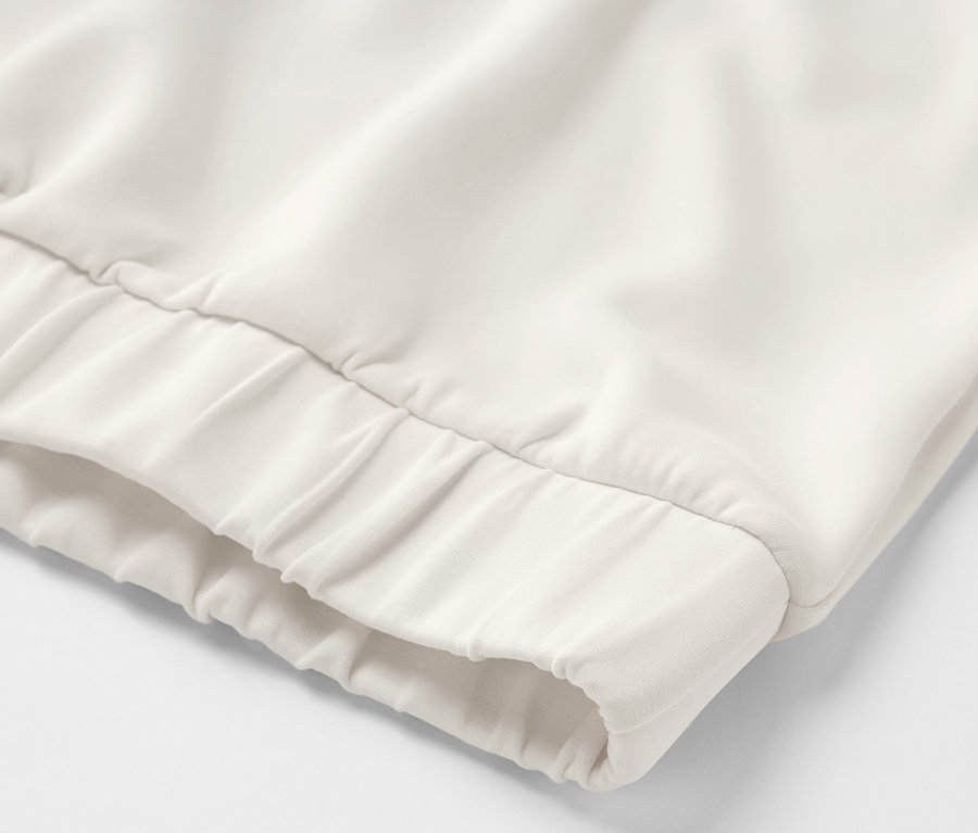 Detail krémově bílé mikiny s kapucí z modalové směsi.