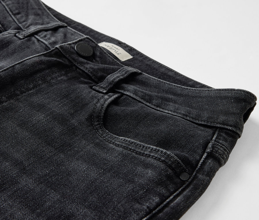 Detail of black jeans with a button closure and front pocket.