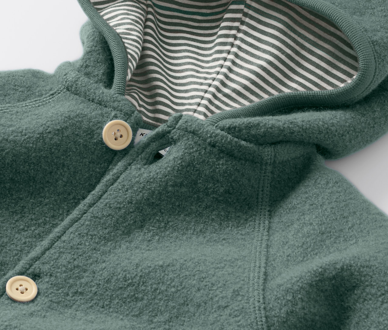 Detailní pohled na overal pro miminka s vlnou merino, zapínaný na knoflíky a s kapucí s pruhovanou podšívkou.