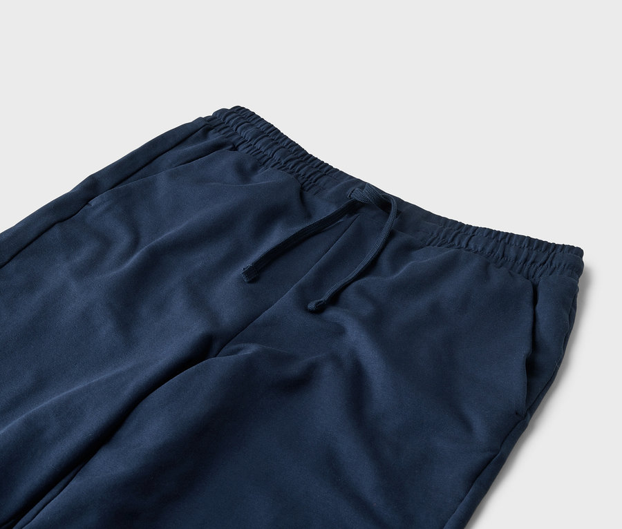 Detailní záběr na tmavě modré tepláky se stahovací šňůrkou a kapsami.