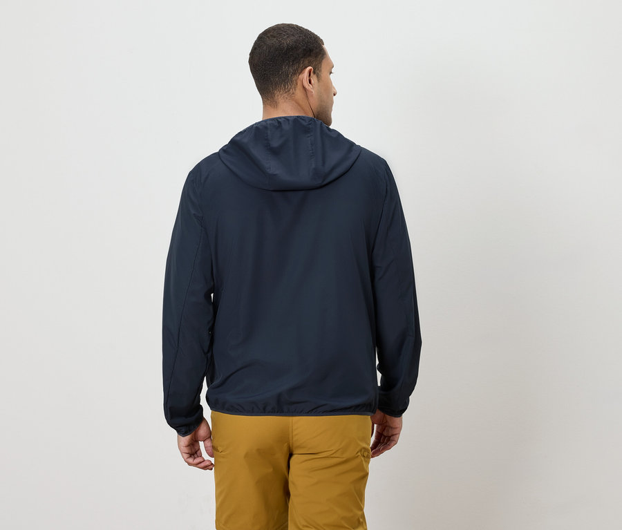 Muž zezadu v tmavě modré bundě s kapucí a žlutých kalhotách.