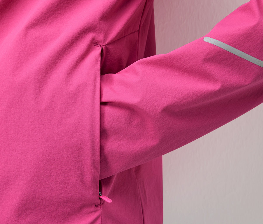 Detail růžové bundy s reflexním pruhem na rukávu.