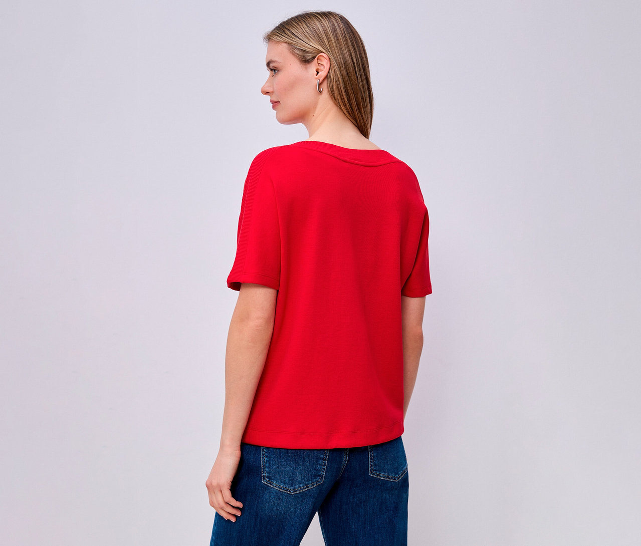 Žena zezadu v červeném tričku s krátkým rukávem Street One a džínách.