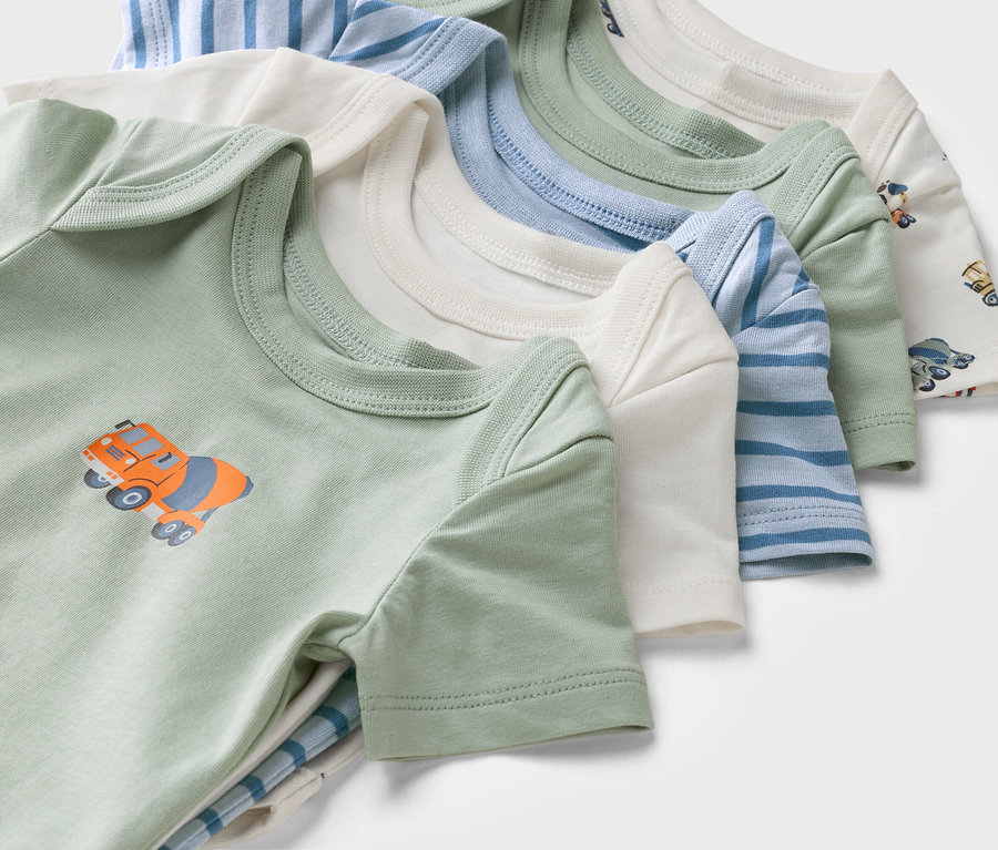 Detailní záběr na dětské body s krátkým rukávem v různých barvách a vzorech, včetně zeleného body s motivem domíchávače betonu.