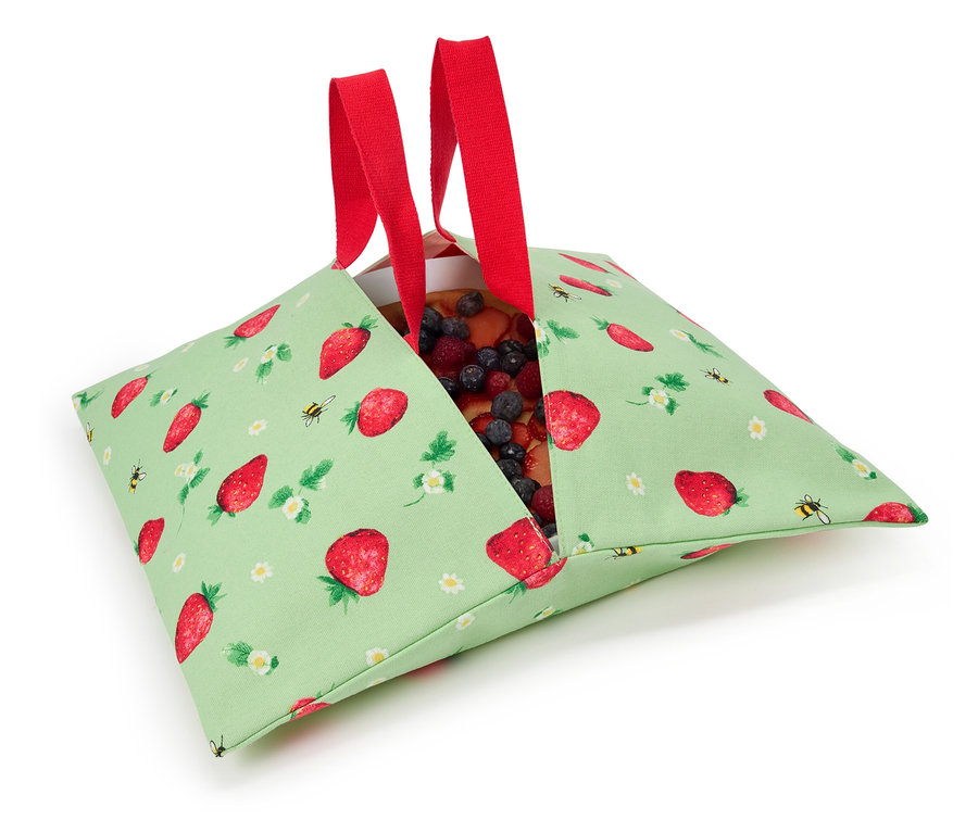 Jahodový koláč v zelené látkové tašce s jahodovým vzorem a červenými uchy.