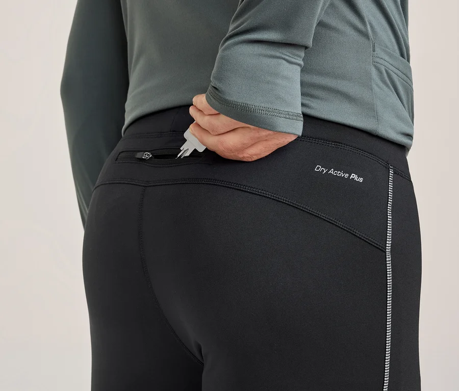 Osoba zezadu vkládá klíče do zadní kapsy na zip černých sportovních kalhot. Kalhoty mají nápis „Dry Active Plus“ a reflexní proužek.