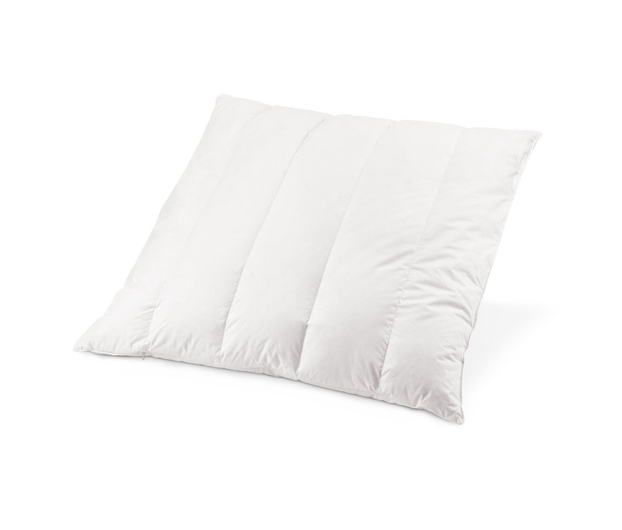 Detailní záběr bílého prošívaného polštáře s vločkami ze dřeva limby.