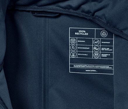 Detailní záběr na vnitřní štítek kombinézy do deště s ikonami a textem o recyklaci, voděodolnosti a prodyšnosti.