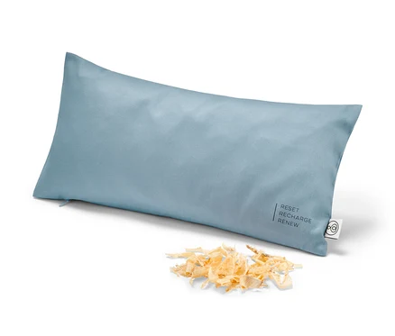 Světle modrý limbový polštářek cca 40 × 20 cm leží na bílém pozadí vedle hromádky hoblin.