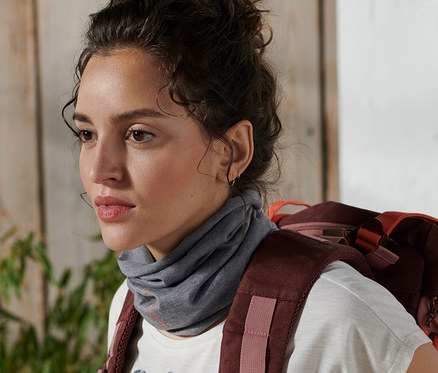 Žena s batohem má na krku multifunkční šátek.