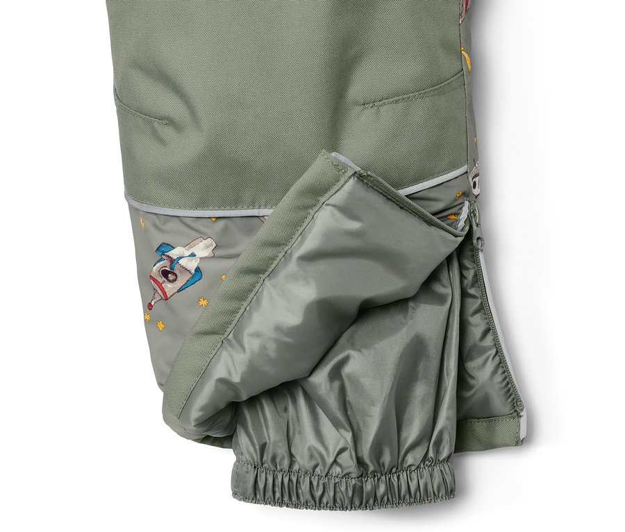 Detail dětské zimní kombinézy s motivem vesmíru a rozepnutým zipem.