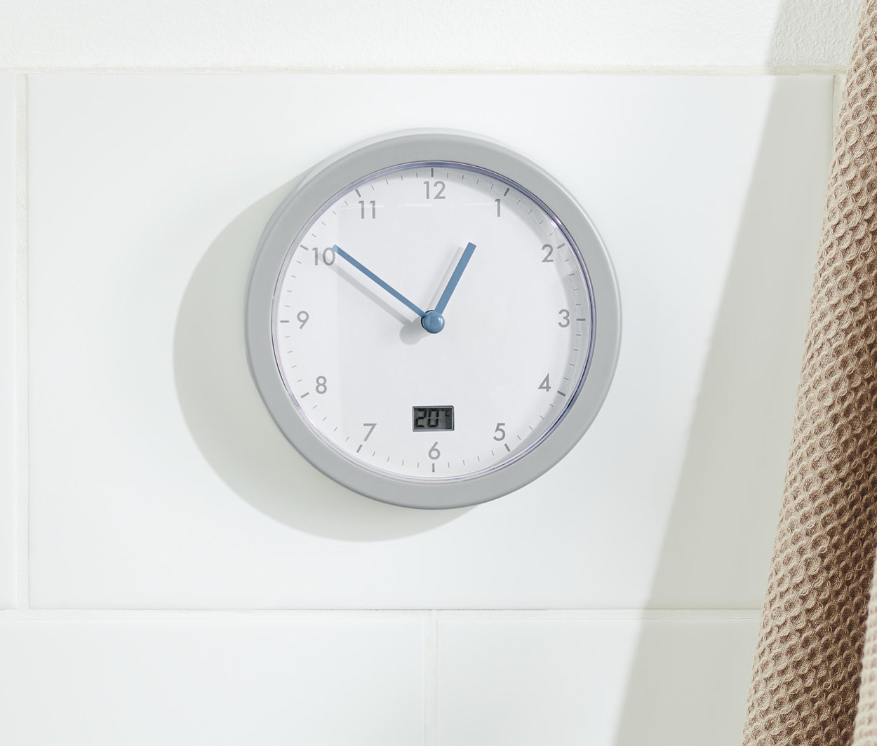 Koupelnové nástěnné hodiny visí na zdi vedle dřevěného žebříku s béžovou osuškou.