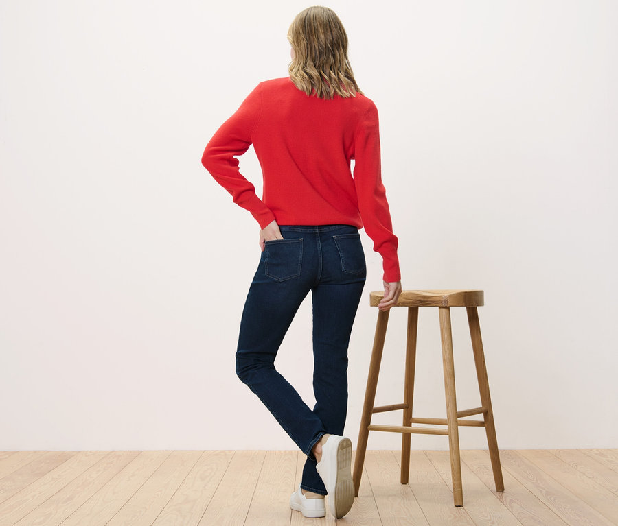 Žena stojí zády k fotoaparátu a má na sobě džíny Slim – Fit »Emma« a červený svetr.