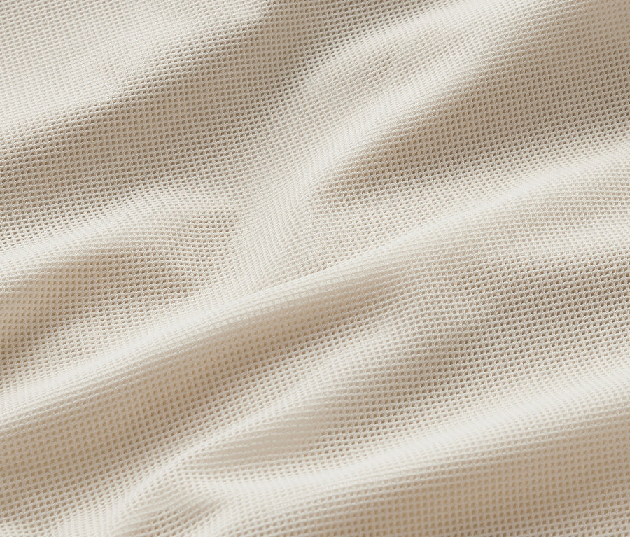 Detail krémové větrovzdorné běžecké bundy.