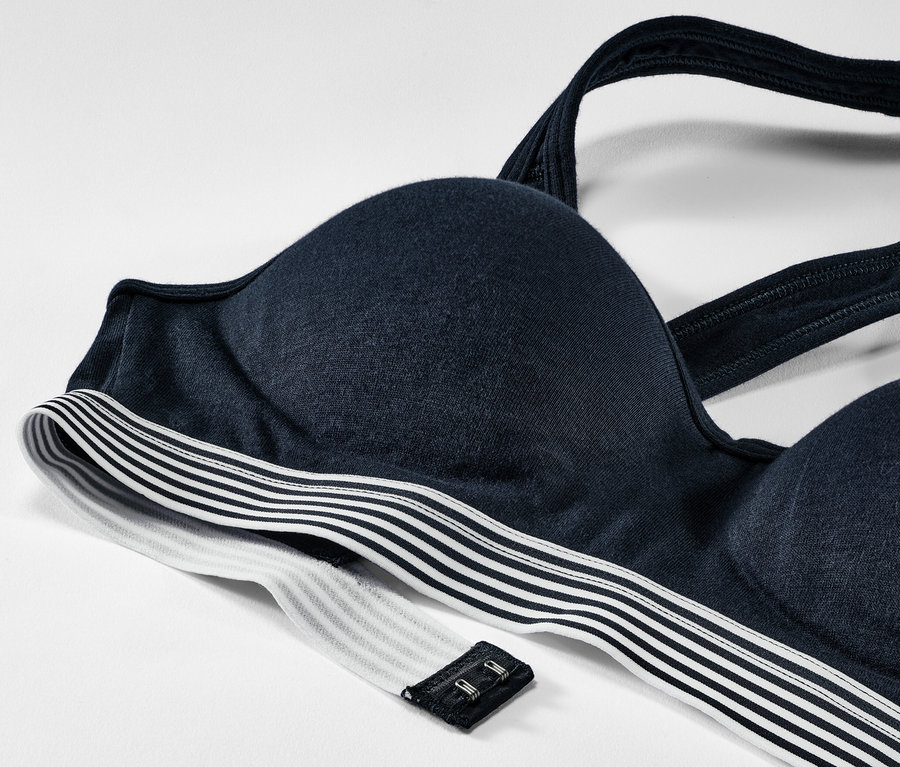 Detail modré podprsenky s vyztuženými košíčky a střihem racerback na bílém pozadí.