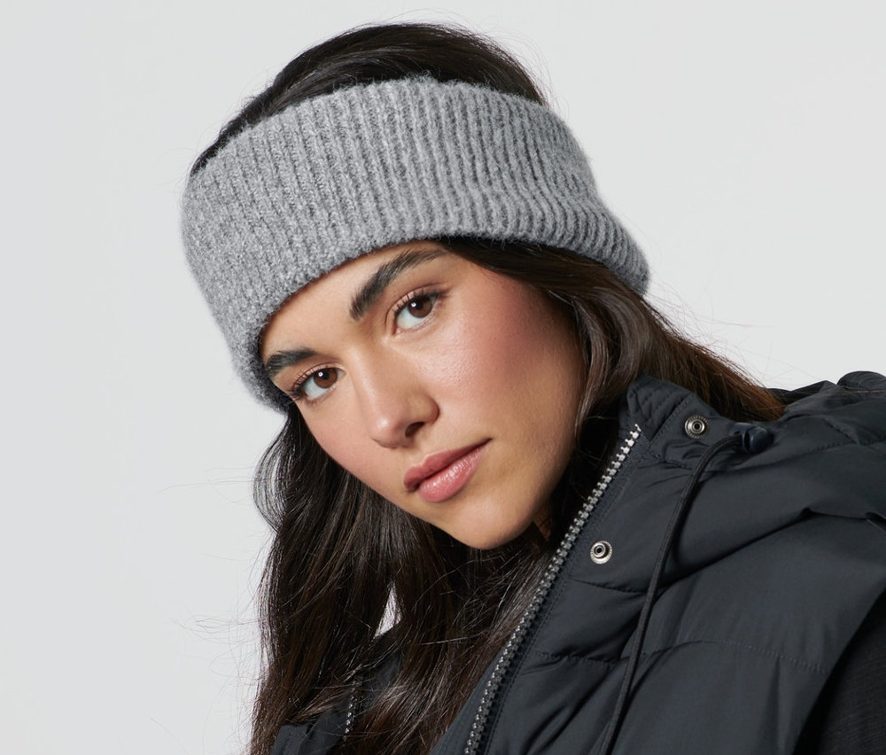 Žena má na sobě pletenou čelenku a černou vestu.