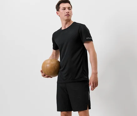 Muž drží basketbalový míč a má na sobě černé funkční triko.