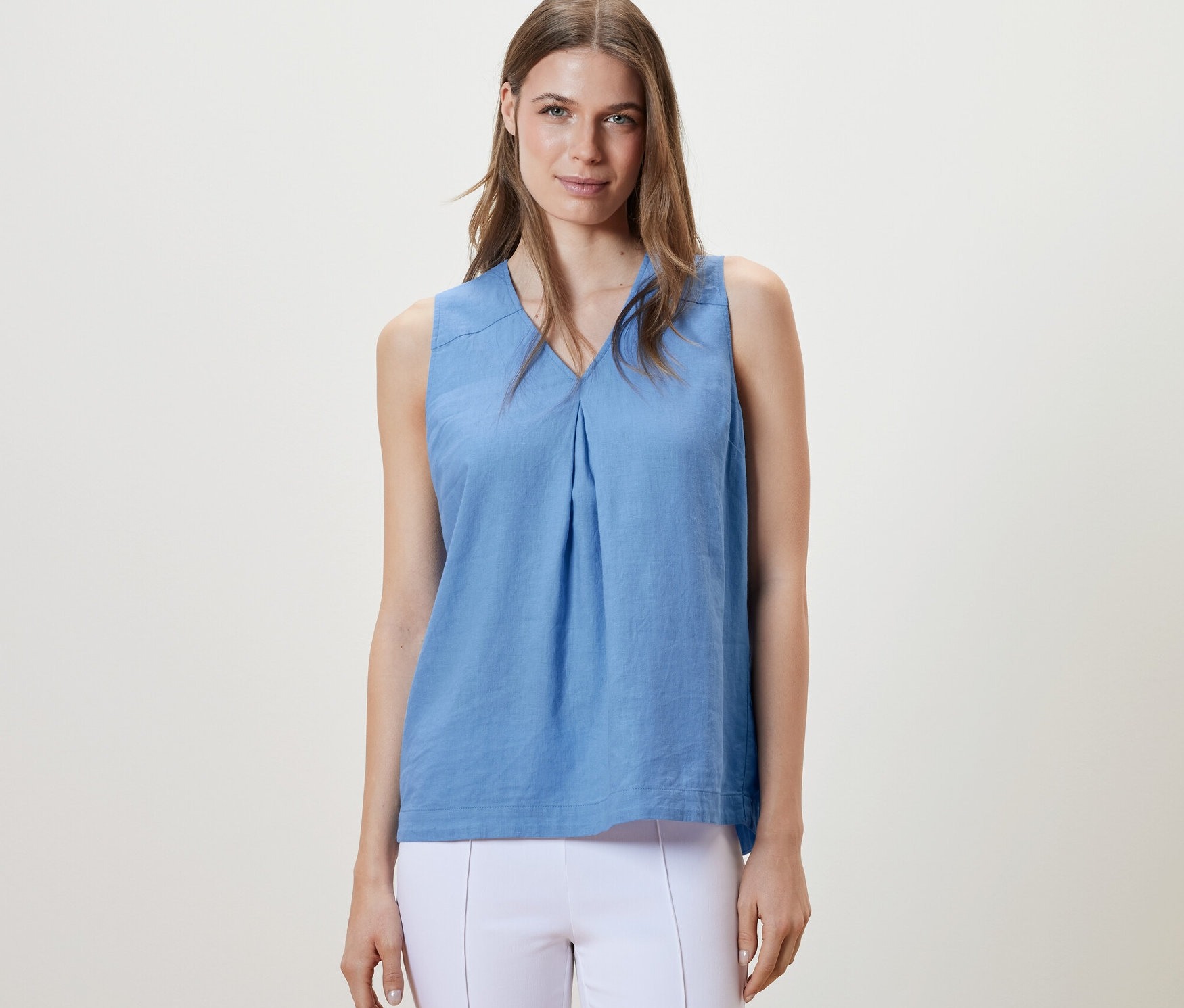 Žena má na sobě světle modrou lněnou halenku bez rukávů.