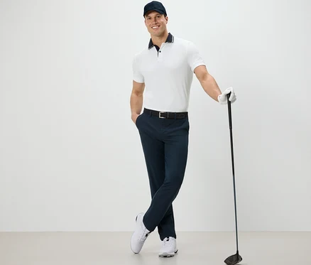Muž pózuje s golfovou holí a má na sobě outdoorové kalhoty.