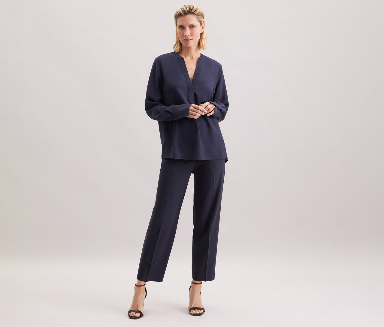 Žena stojí a má na sobě tmavě modrou tuniku z viskózy Seidensticker.