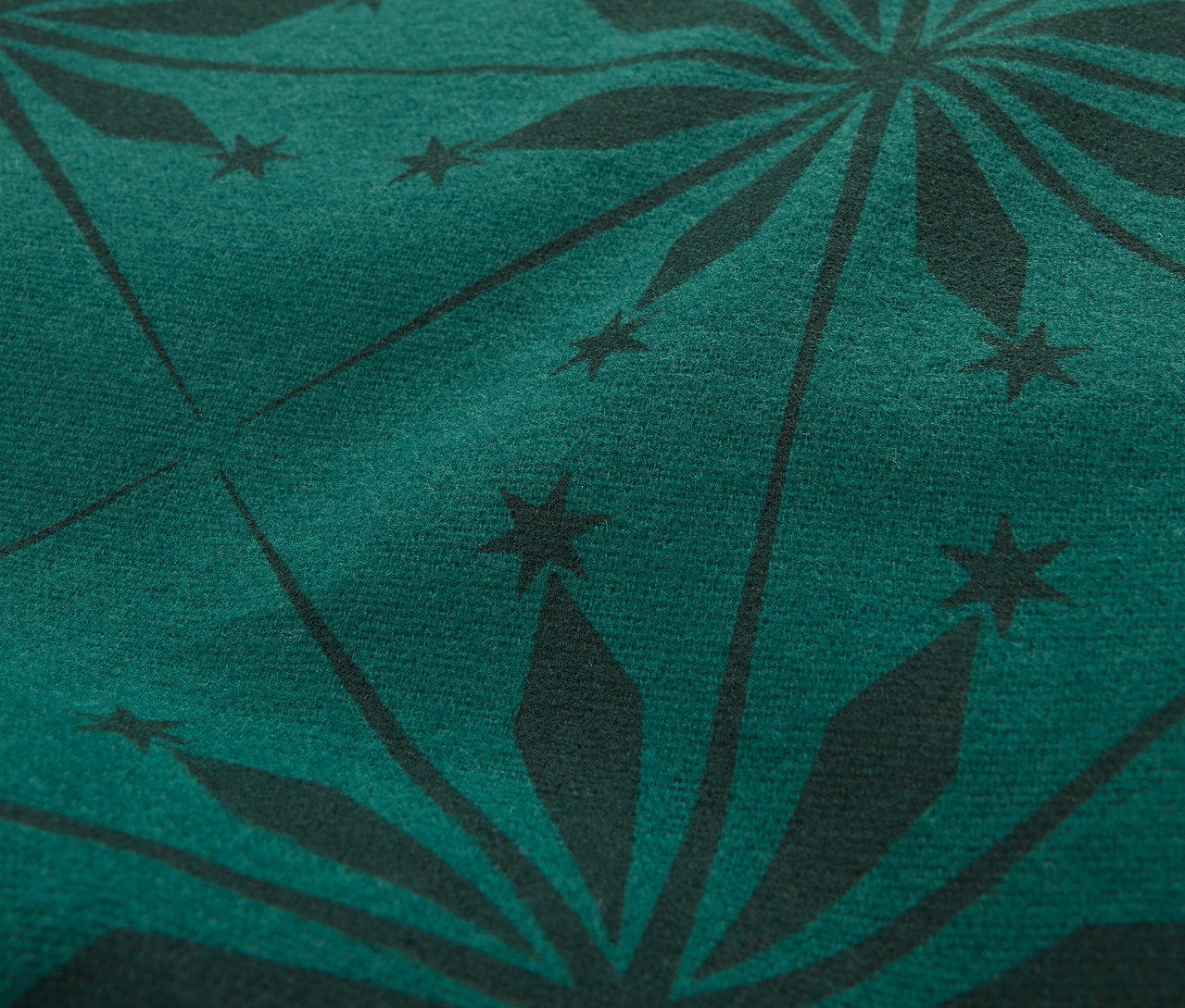 Detailní záběr na tmavě zelenou látku s černým vzorem hvězdic.