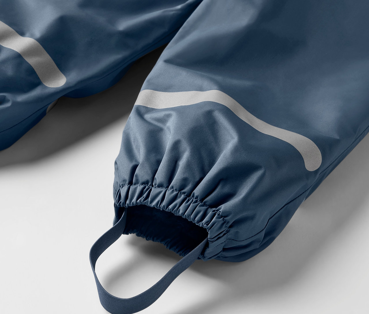 Detail modrých dětských termo kalhot do deště s reflexními prvky a elastickými lemy.