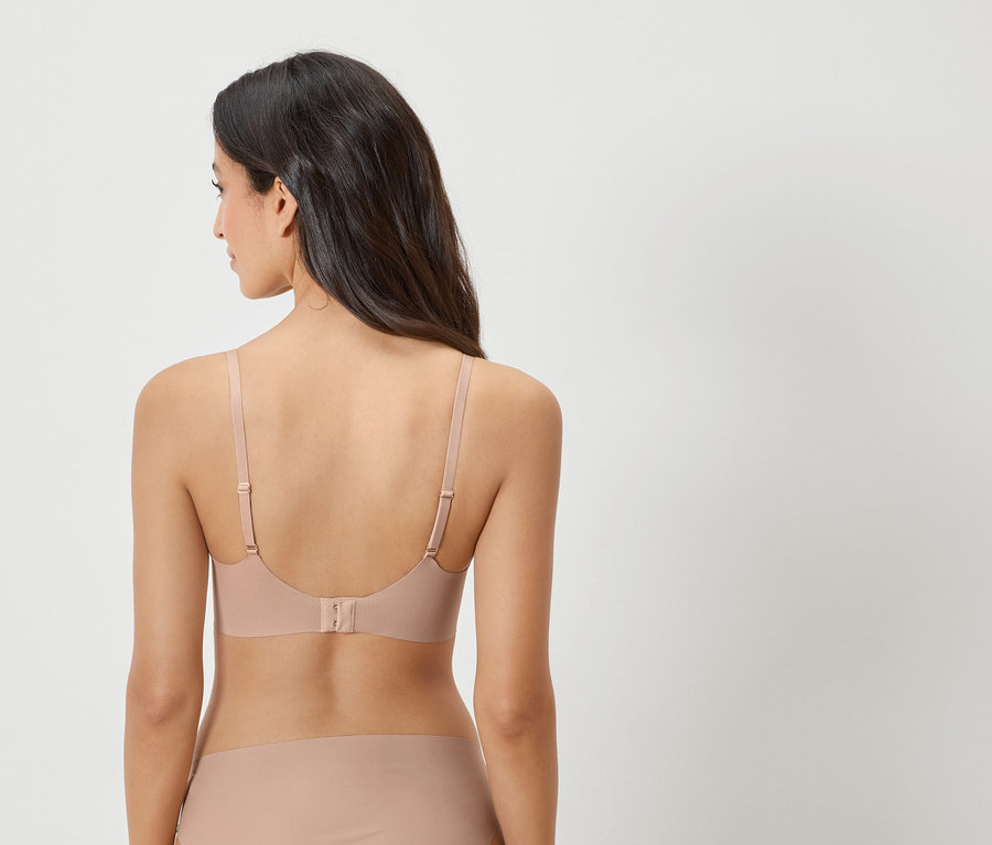 Pohled zezadu na ženu s tmavými vlasy v tělové podprsence a odpovídajících kalhotkách.