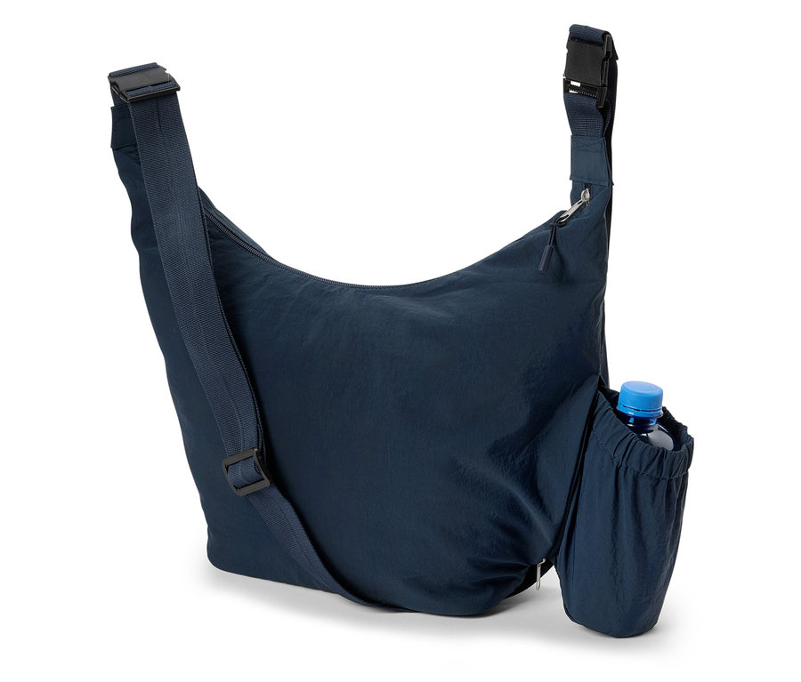 Detailní záběr na tmavě modrou tašku přes rameno s lahví vody v boční kapse.