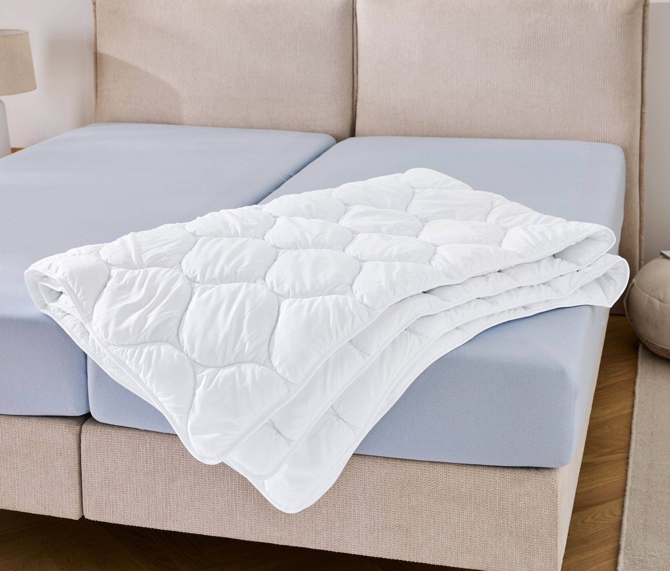 Na modrém prostěradle leží složená přikrývka odolná proti varu v nadměrné velikosti.