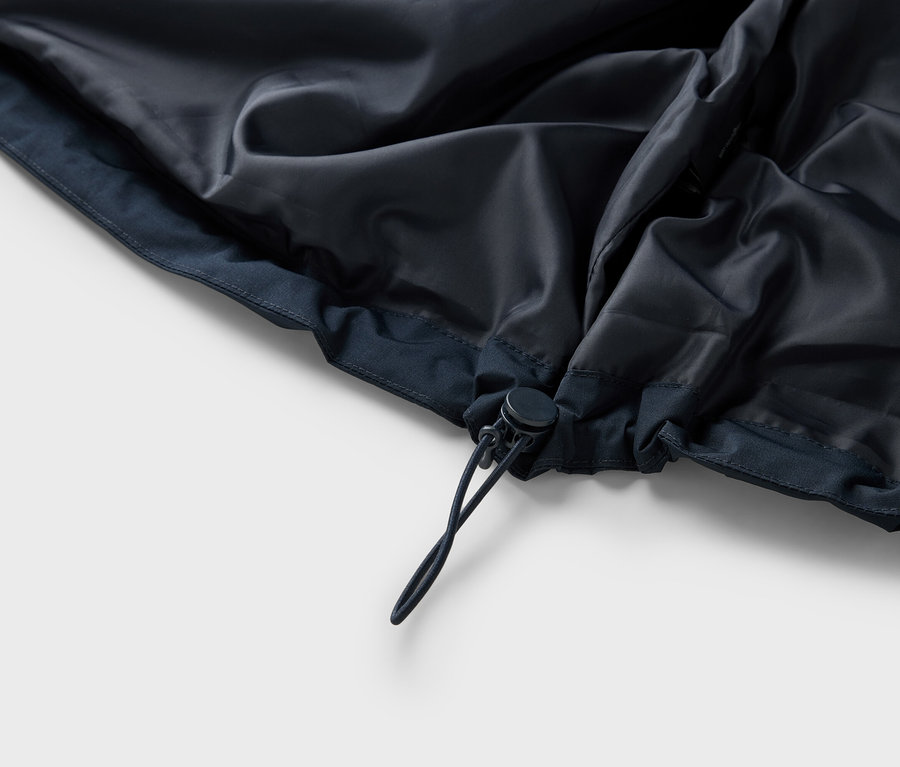 Detailní pohled na vnitřek tmavě modré bundy se stahovací šňůrkou.