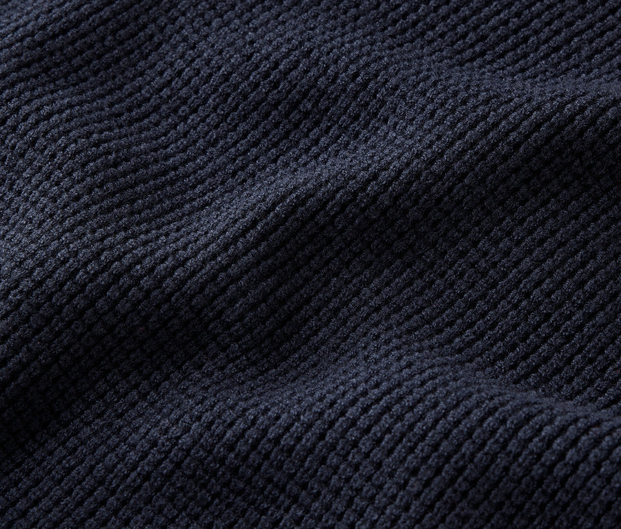 Detail tmavě modré manšestrové látky se záhyby.