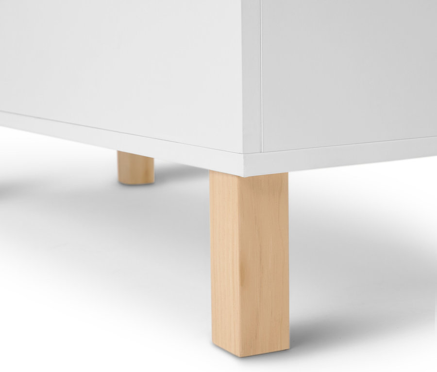 Detailní pohled na bílý nábytek se světlými dřevěnými nohami.