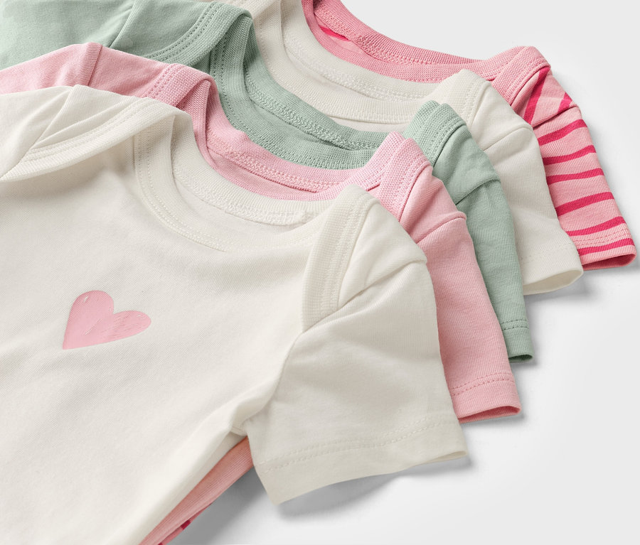 Vícebarevné dětské body s krátkým rukávem jsou naskládané na sobě.