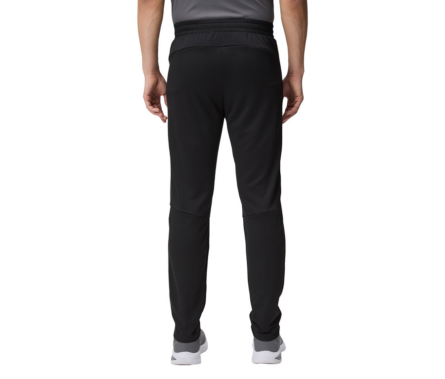 Detailní záběr na zadní část osoby v černých teplácích a šedých botách.