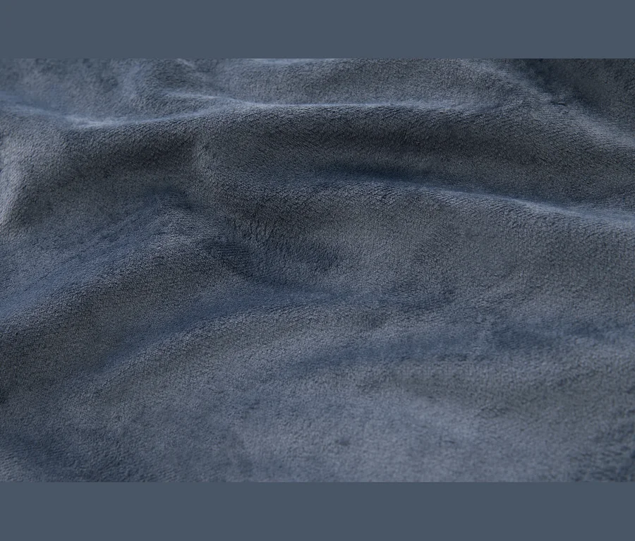 Detail měkké, texturované modré látky s viditelnými záhyby a pomačkáním.