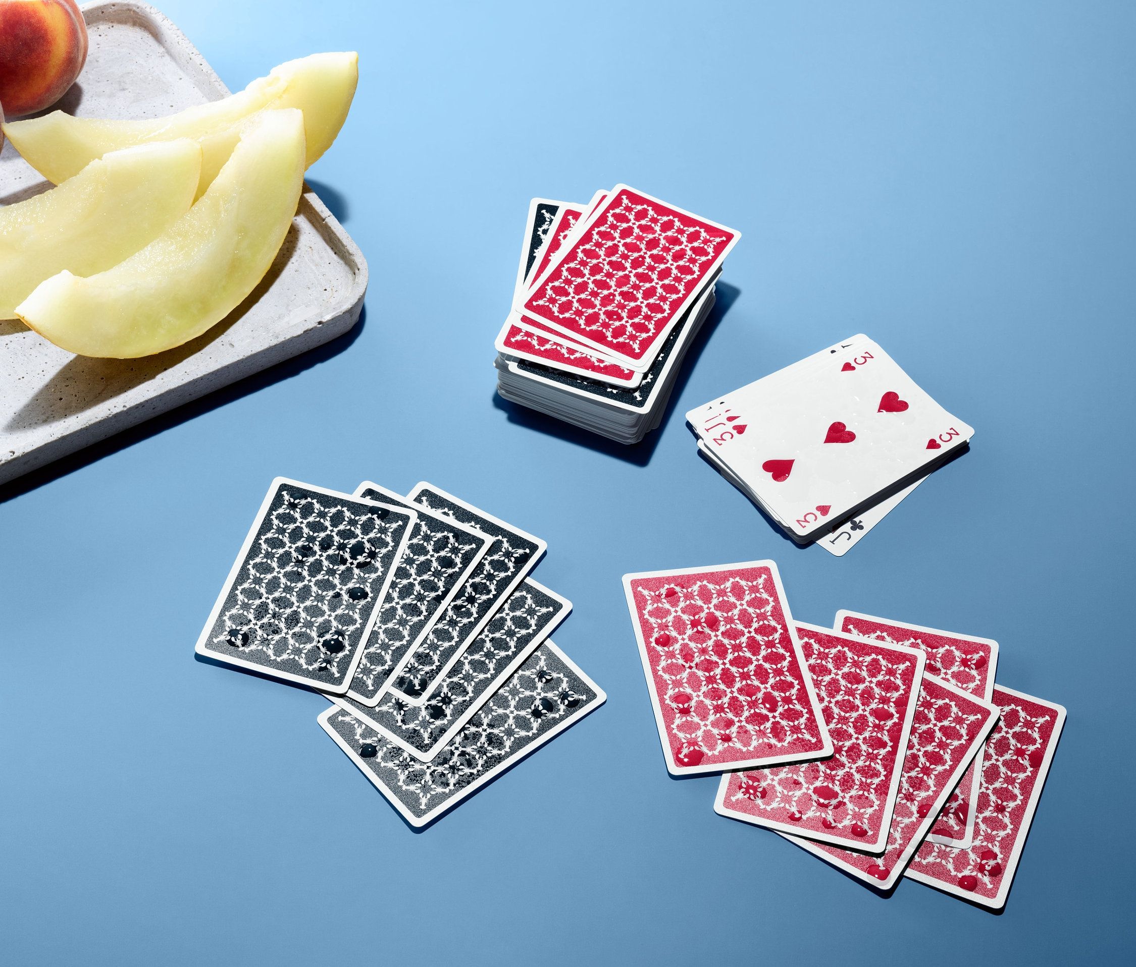 Na modrém pozadí jsou voděodolné hrací karty a ovoce.
