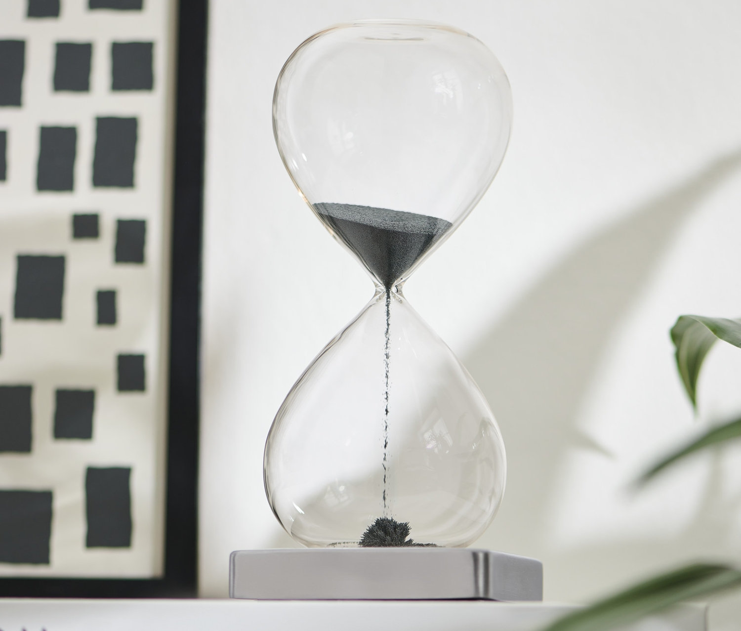 Černé magnetické přesýpací hodiny na bílé knize.