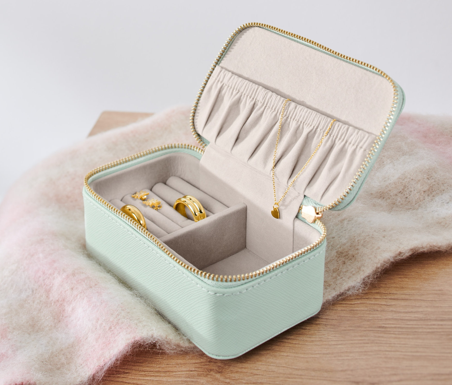 Otevřená malá šperkovnice s prsteny, náušnicemi a náhrdelníkem.