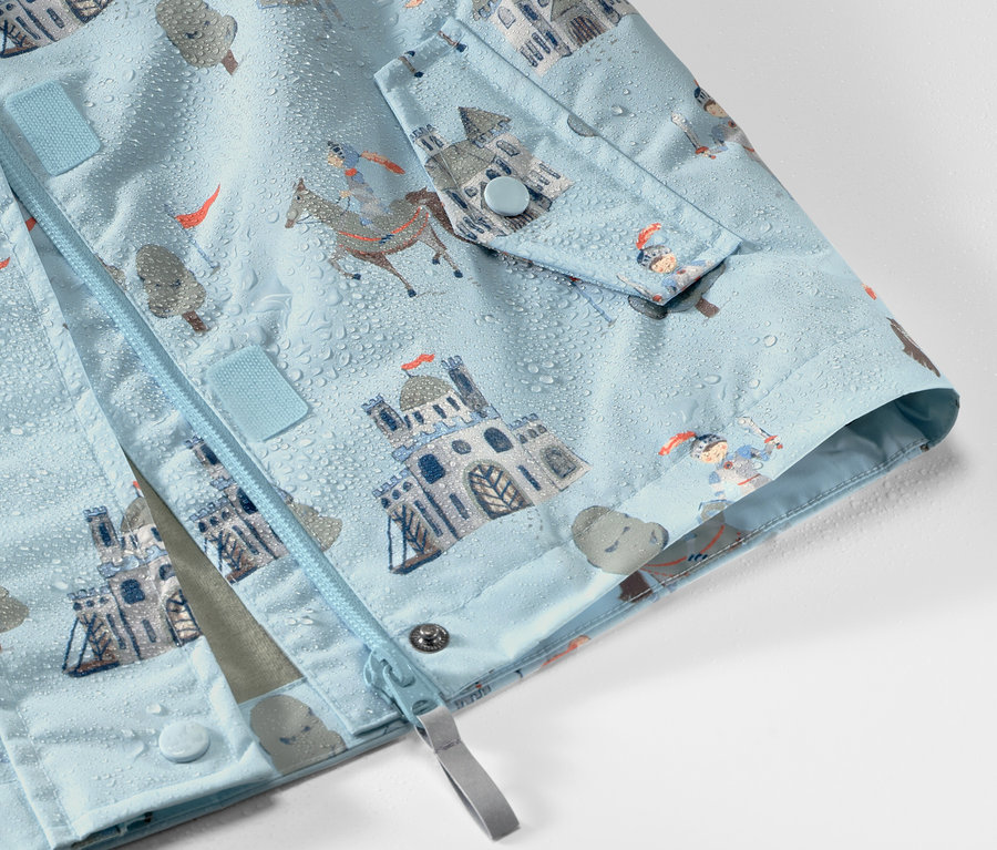 Detail dětské bundy do deště s motivem rytíře, na které jsou kapky vody.