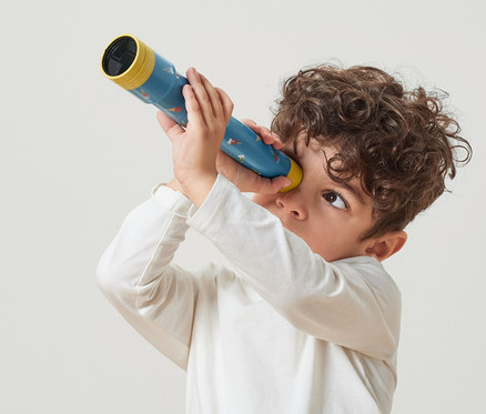 Chlapec se dívá skrz dětský dalekohled.