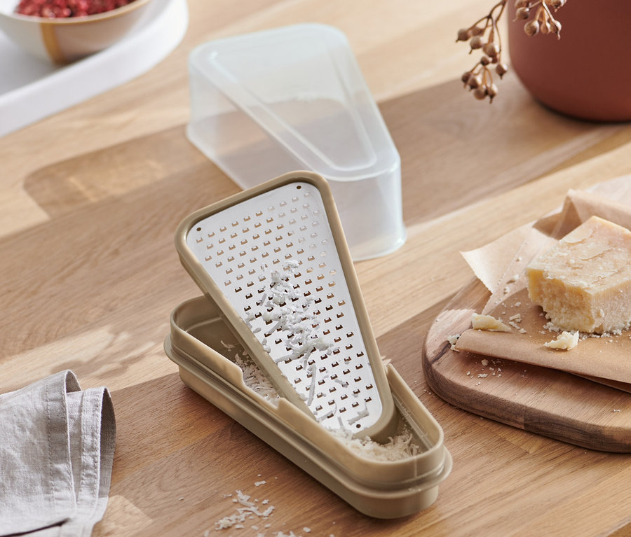 Pohled shora na 2 v 1 struhadlo na parmezán s nádobou na dřevěném stole spolu s jídlem.