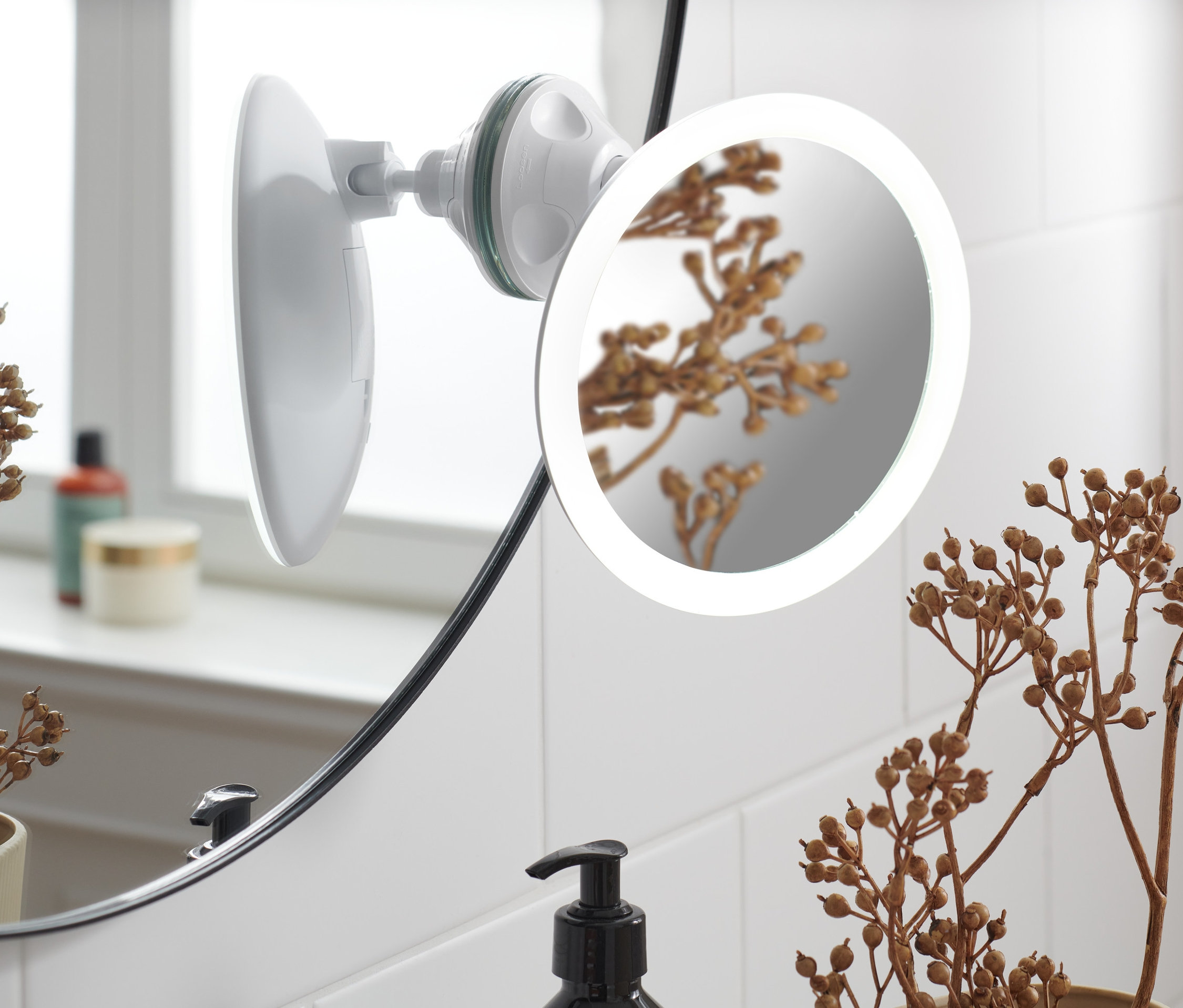 Detailní pohled na kosmetické zrcátko s LED připevněné na dlaždicové zdi.