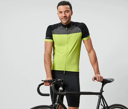 Muž pózuje s kolem a má na sobě cyklistický trikot.
