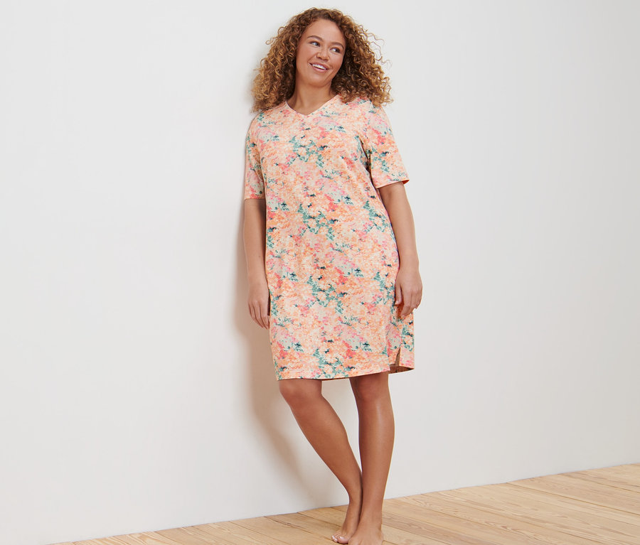 Žena opřená o stěnu v noční košili.