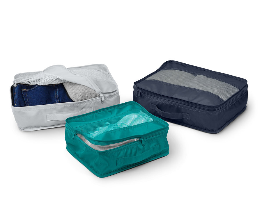 Tři cestovní úložné tašky v šedé, tyrkysové a tmavě modré barvě.