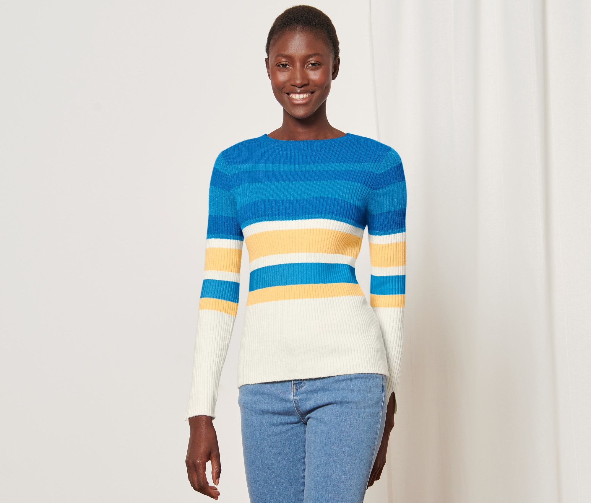 Žena má na sobě žebrovaný svetr přes hlavu s modrými, žlutými a bílými vodorovnými pruhy.