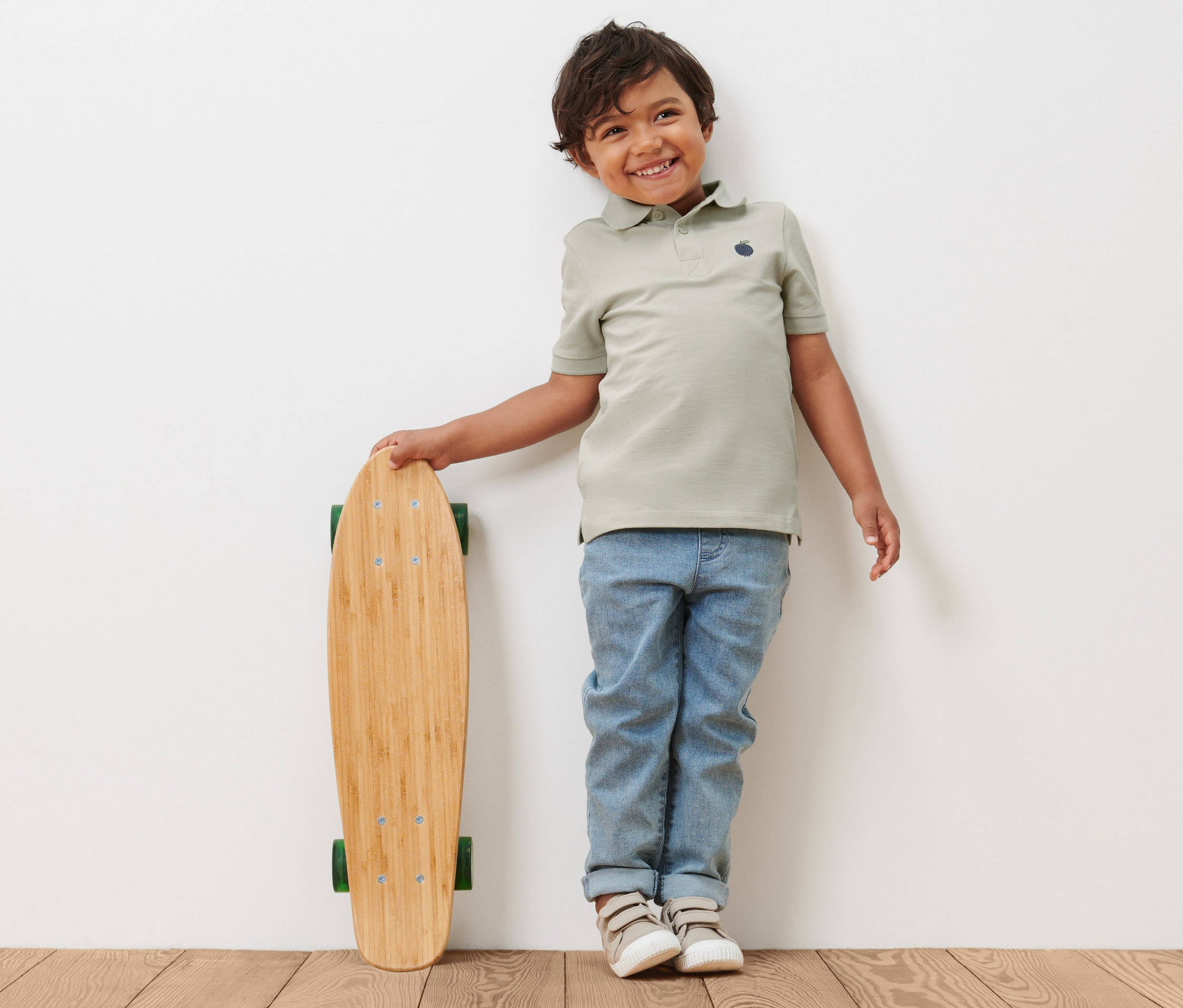 Chlapec v dětském polo tričku (2 ks) se opírá o skateboard.