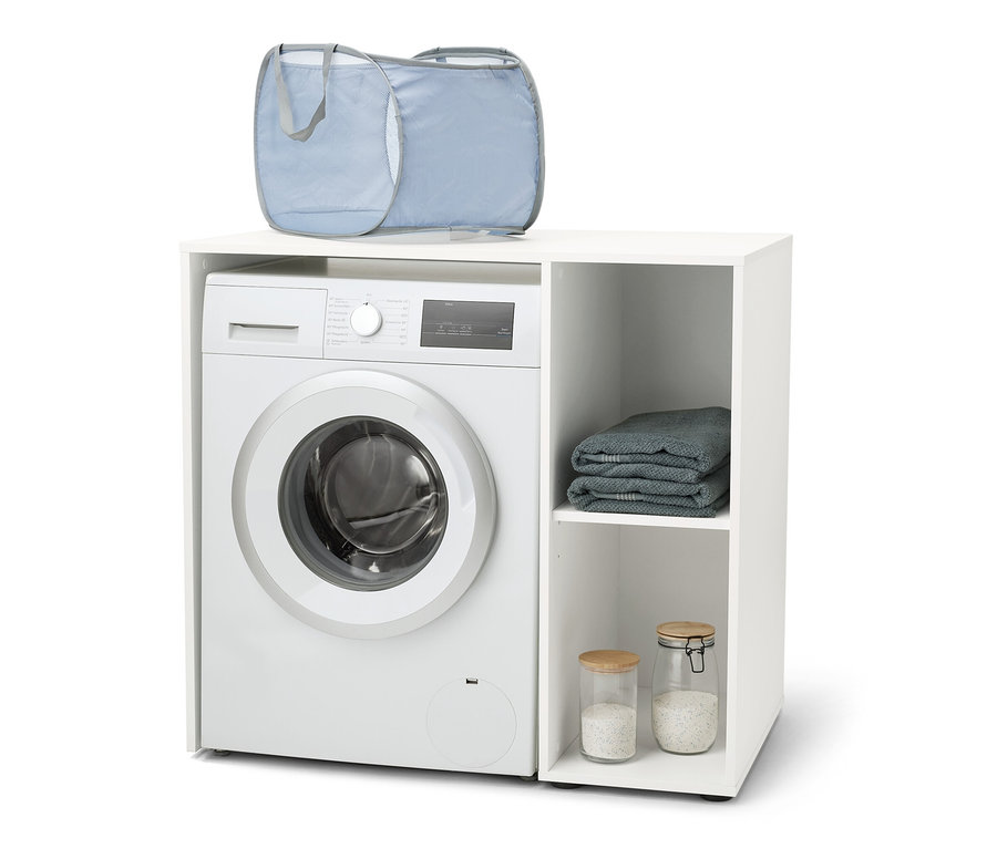 Pračka je umístěna v bílém regálu na pračku s bočním úložným prostorem. Na pračce je položen modrý koš na prádlo.