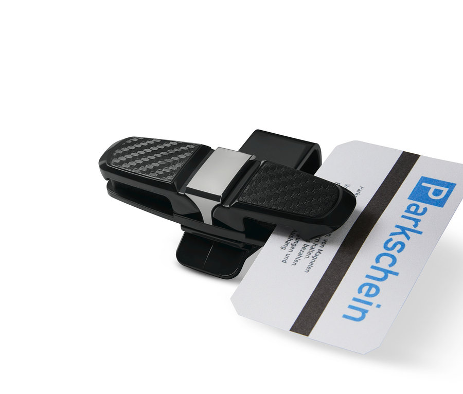 Černý držák brýlí do auta drží parkovací kartu.