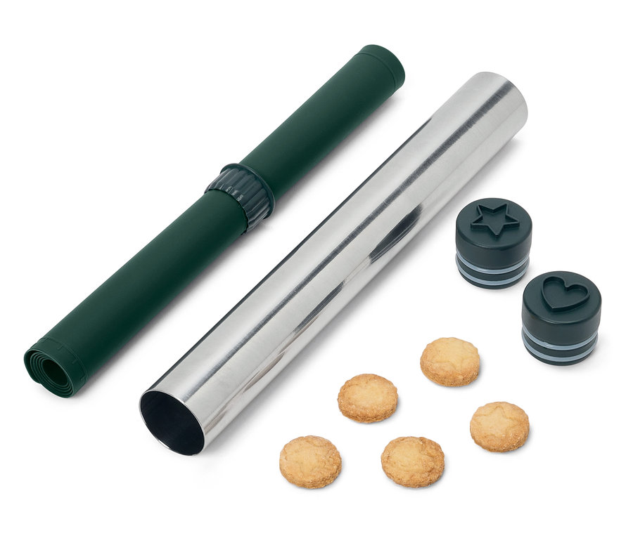 Zelená rolovací podložka a stříbrný váleček s vykrajovátky na sušenky ve tvaru hvězdy a srdce a sušenkami.